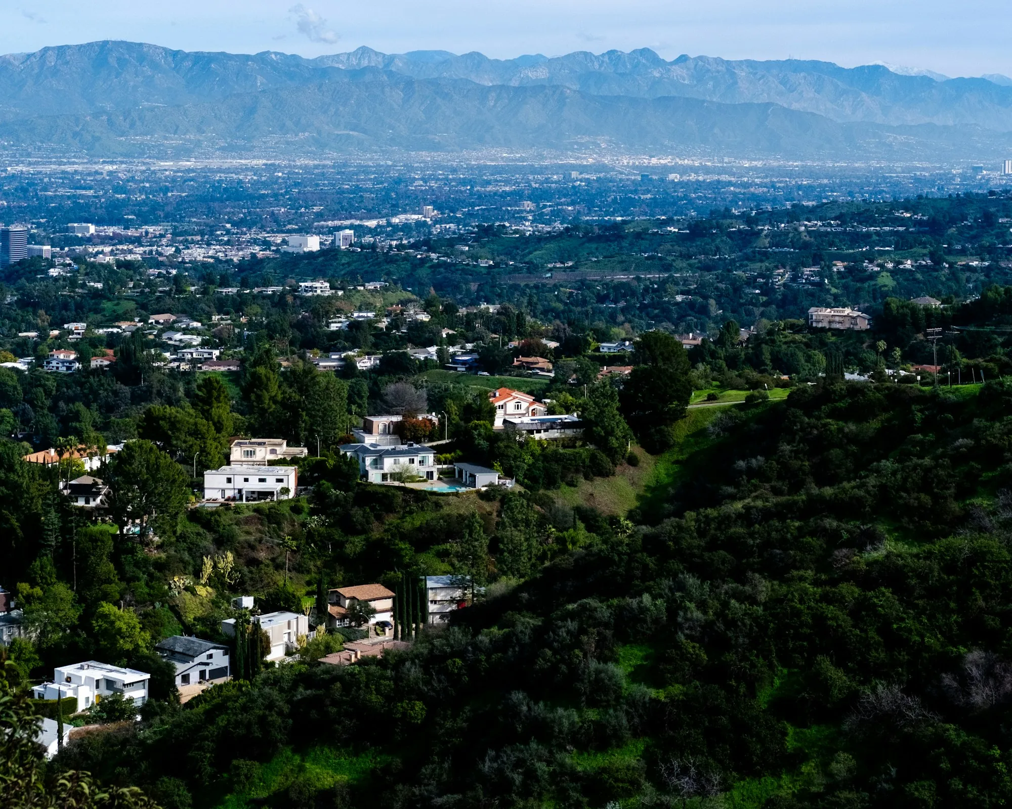 Suburban homes in rolling green hills with mountains behind